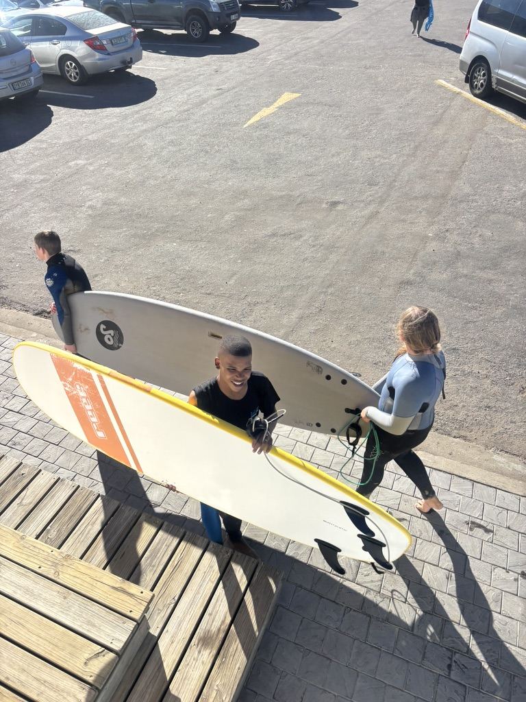 Radical Rippers staff carrying rental surfboards to the beach